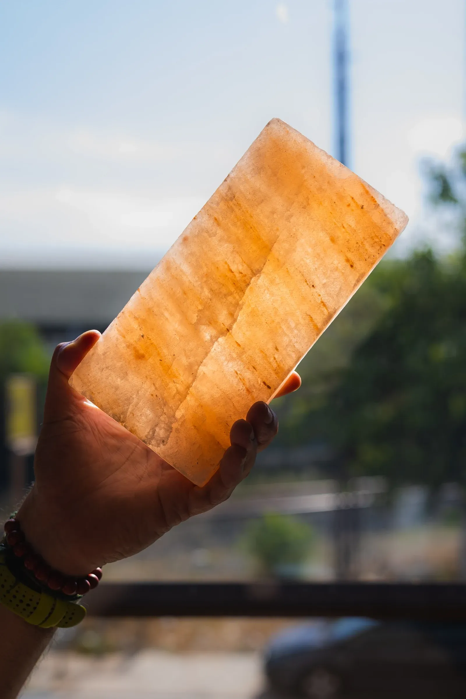 Una mano sostiene una pieza de Piedra del Himalaya Coral a contraluz